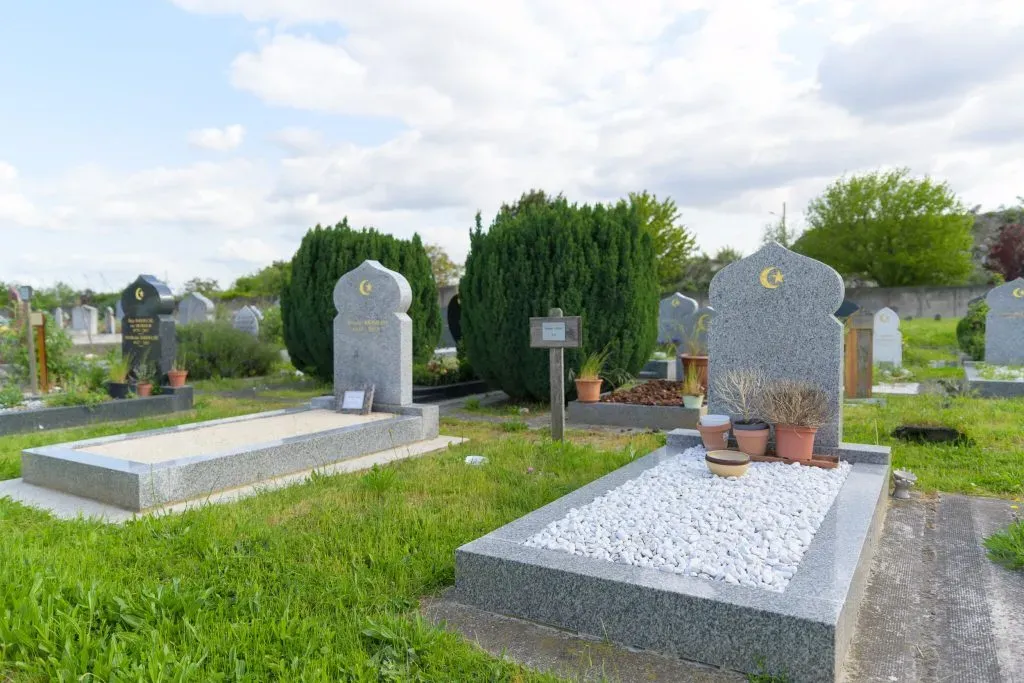 Tombes musulmanes en granit ornées de stèles à dôme et croissants dorés dans un cimetière